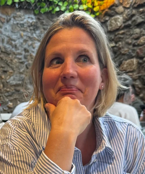 Petra op de foto die een gekke bek trekt. Ze draagt een blauw wit gestreepte blouse en de achtergrond is grof gesteente.